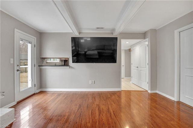 unfurnished living room with beamed ceiling and light wood-type flooring