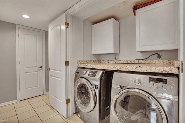 laundry room featuring cabinets, light tile patterned floors, and washer and clothes dryer