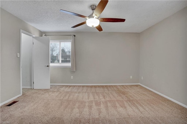 spare room with ceiling fan, light colored carpet, and a textured ceiling