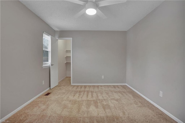 carpeted spare room with a textured ceiling and ceiling fan