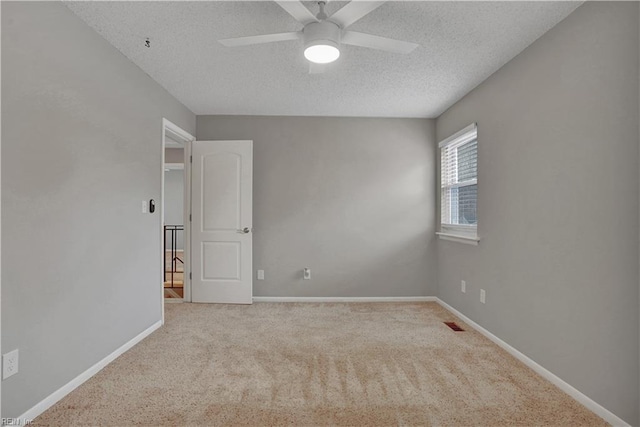 empty room with light colored carpet, a textured ceiling, and ceiling fan