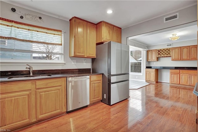 kitchen with ornamental molding, appliances with stainless steel finishes, sink, and light wood-type flooring