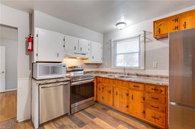 kitchen with white cabinetry, appliances with stainless steel finishes, sink, and light hardwood / wood-style flooring