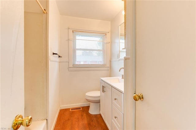 bathroom featuring vanity, wood-type flooring, walk in shower, and toilet