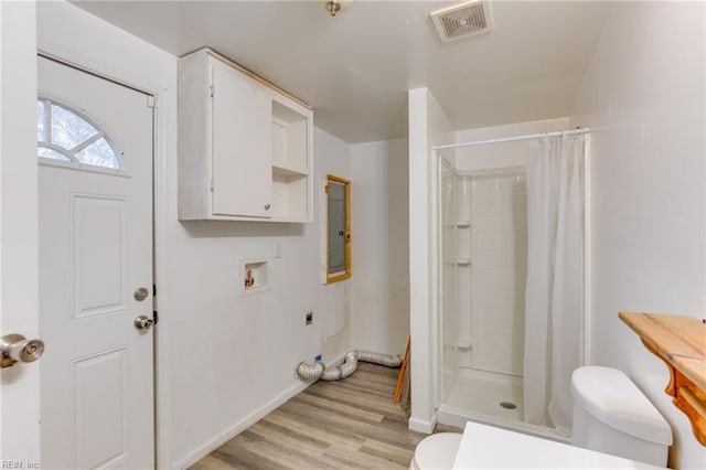 bathroom with hardwood / wood-style floors, electric panel, toilet, and walk in shower