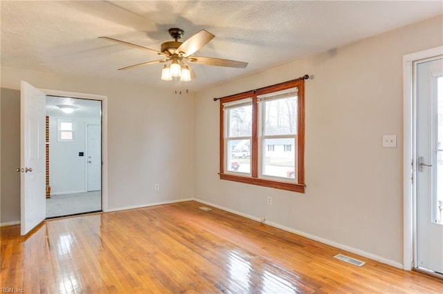 empty room featuring ceiling fan, a textured ceiling, and light wood-type flooring