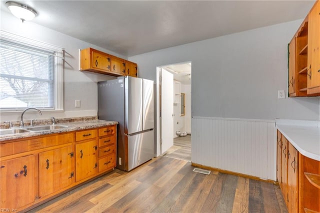 kitchen featuring sink, stainless steel refrigerator, and light wood-type flooring