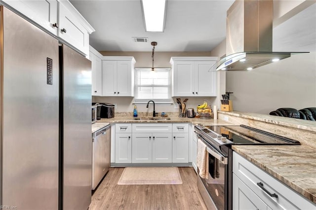 kitchen with appliances with stainless steel finishes, island range hood, hanging light fixtures, and white cabinets