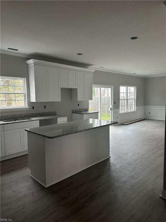 kitchen with white cabinetry, ornamental molding, and a kitchen island