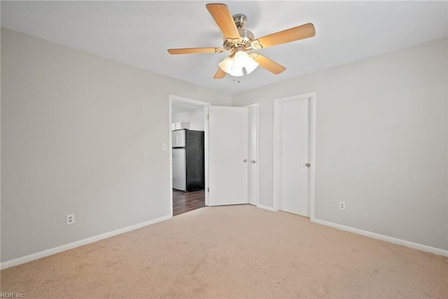 unfurnished bedroom featuring stainless steel fridge, ceiling fan, and carpet