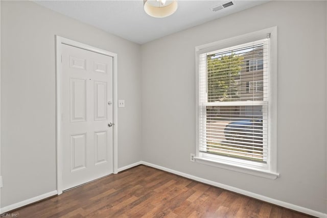 empty room with dark wood-type flooring and a wealth of natural light