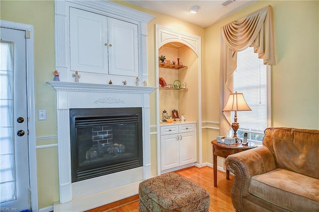 living area with a wealth of natural light, light hardwood / wood-style floors, and built in shelves