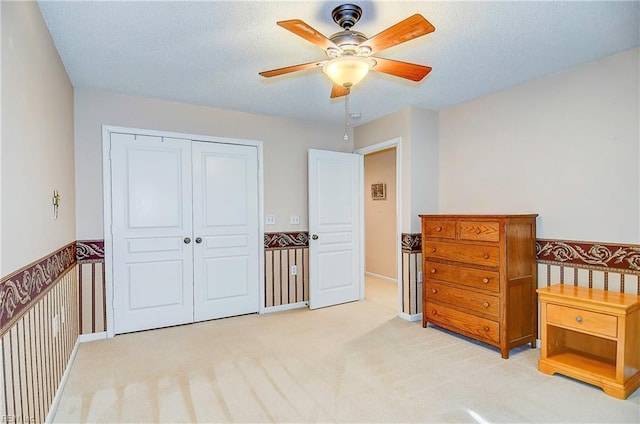 bedroom featuring light carpet, a textured ceiling, ceiling fan, and a closet