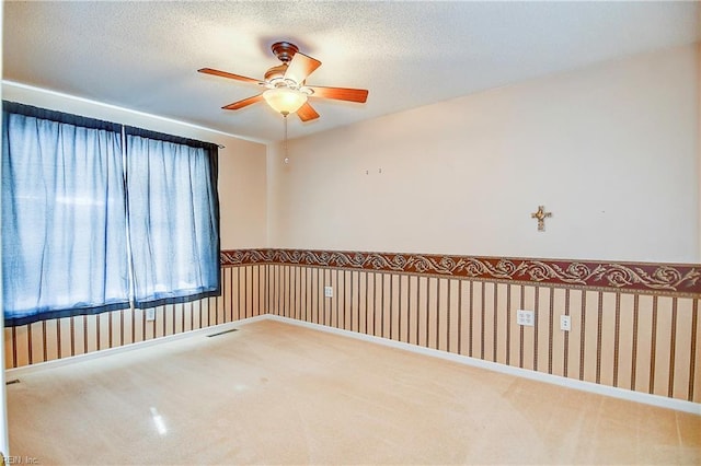 carpeted empty room with ceiling fan and a textured ceiling