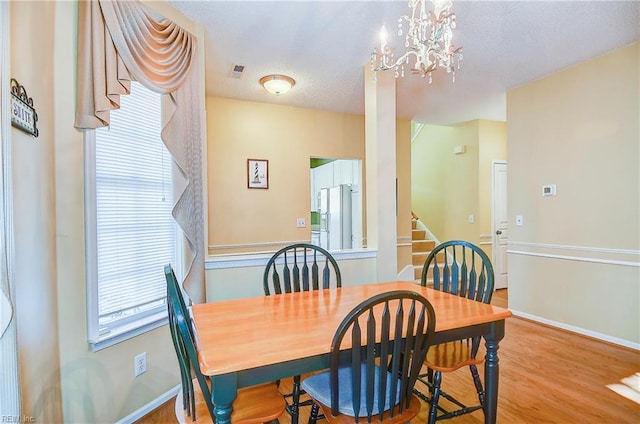 dining space featuring wood-type flooring and an inviting chandelier