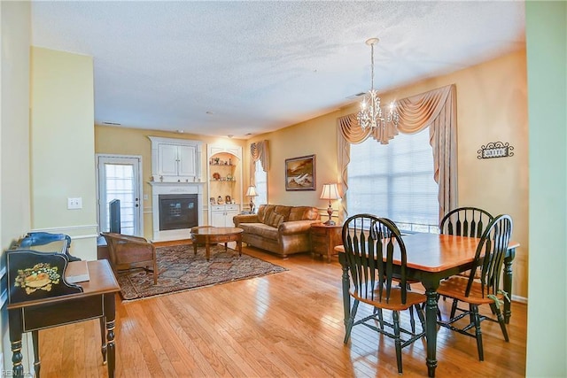 dining room with a textured ceiling, light hardwood / wood-style floors, and a chandelier