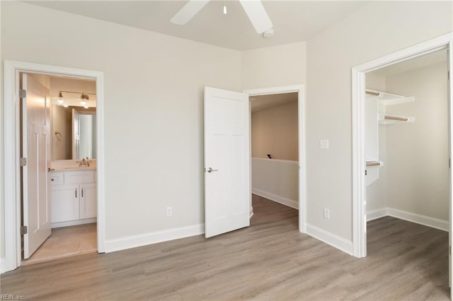 unfurnished bedroom with sink, a spacious closet, and light hardwood / wood-style flooring