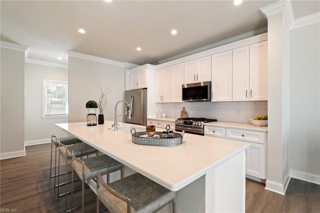 kitchen featuring tasteful backsplash, an island with sink, a breakfast bar area, white cabinets, and stainless steel appliances