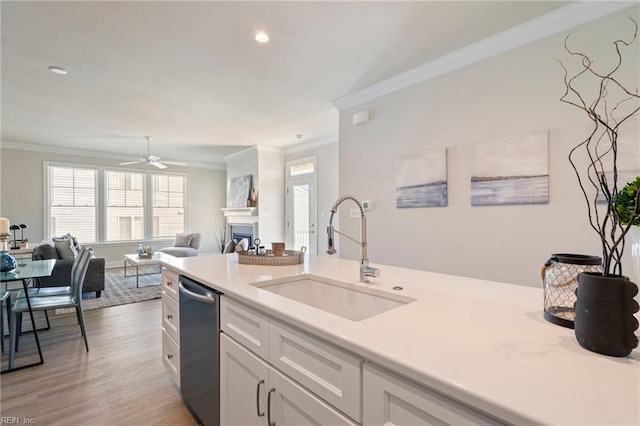 kitchen featuring stainless steel dishwasher, ornamental molding, sink, and white cabinets