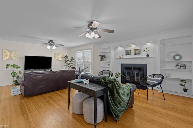 living room featuring ceiling fan, ornamental molding, wood-type flooring, and built in features