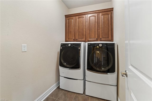 washroom featuring washing machine and dryer, cabinets, and dark tile patterned floors