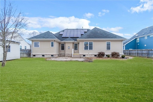 rear view of property featuring a lawn and solar panels