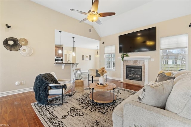 living room featuring a tile fireplace, vaulted ceiling, plenty of natural light, and dark wood-type flooring