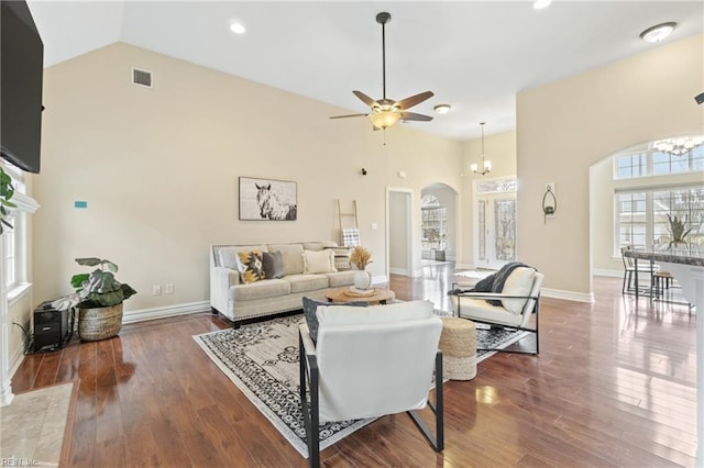 living room featuring ceiling fan with notable chandelier, dark hardwood / wood-style flooring, and high vaulted ceiling