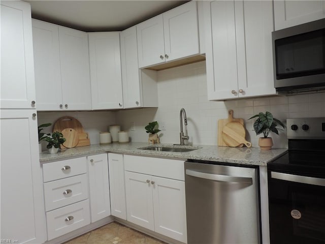 kitchen with sink, white cabinetry, light stone counters, appliances with stainless steel finishes, and backsplash