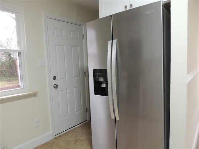 kitchen featuring stainless steel fridge with ice dispenser, light tile patterned floors, and white cabinets