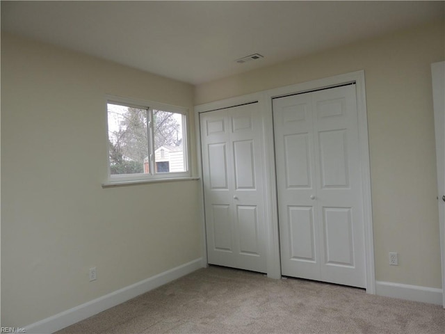 unfurnished bedroom featuring multiple closets and light colored carpet