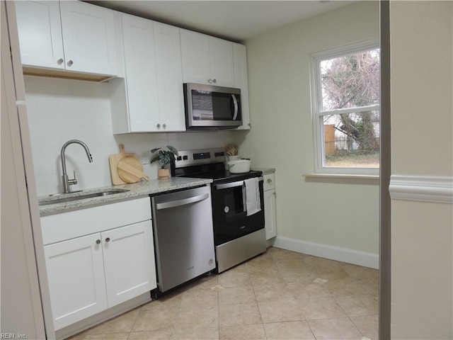 kitchen featuring sink, white cabinetry, light stone counters, appliances with stainless steel finishes, and decorative backsplash