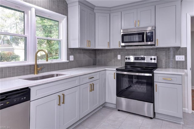 kitchen featuring light tile patterned flooring, appliances with stainless steel finishes, sink, and backsplash