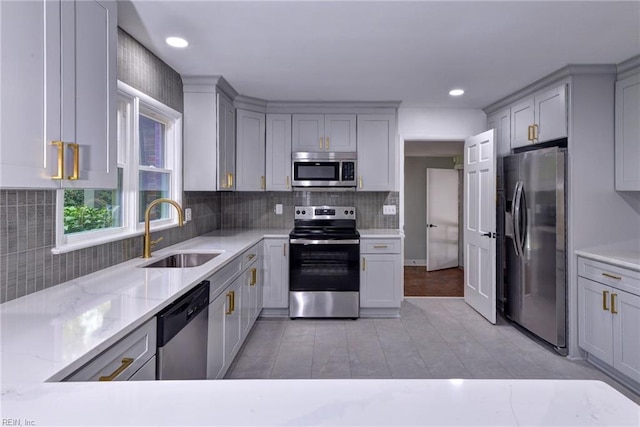 kitchen featuring tasteful backsplash, stainless steel appliances, sink, and gray cabinetry