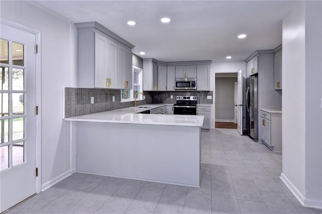 kitchen featuring appliances with stainless steel finishes, gray cabinets, kitchen peninsula, and sink