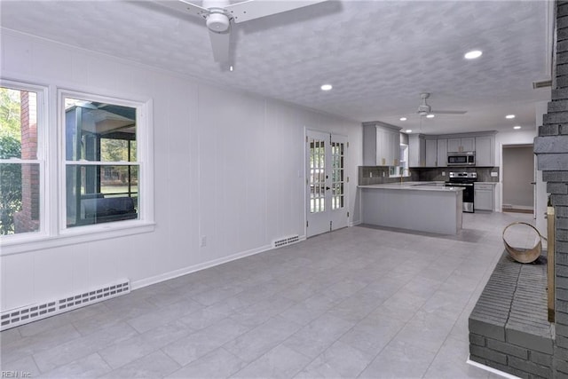 unfurnished living room featuring a baseboard radiator, sink, and ceiling fan