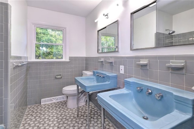 bathroom with tile patterned flooring, sink, tile walls, and walk in shower