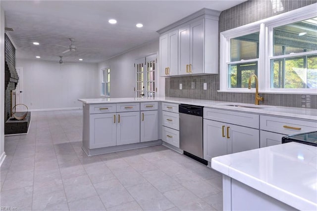 kitchen with sink, dishwasher, tasteful backsplash, a brick fireplace, and kitchen peninsula