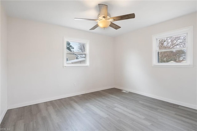 unfurnished room with ceiling fan, plenty of natural light, and wood-type flooring