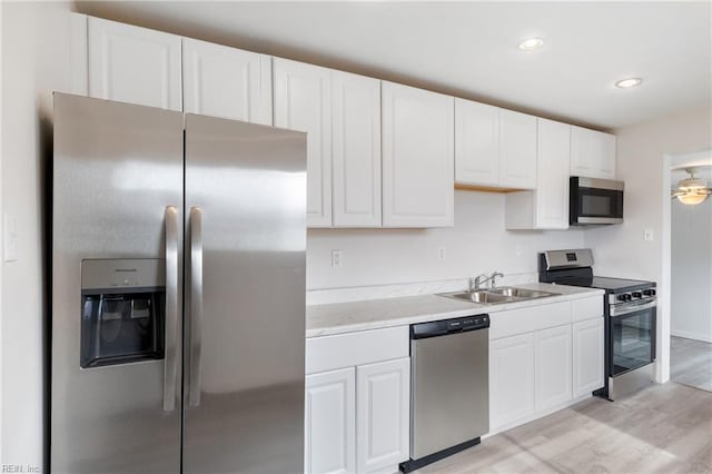 kitchen featuring sink, ceiling fan, stainless steel appliances, light hardwood / wood-style floors, and white cabinets