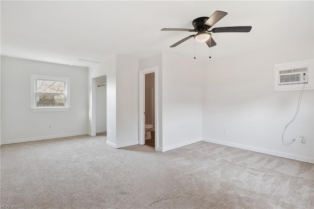 spare room with ceiling fan, light colored carpet, and a wall unit AC