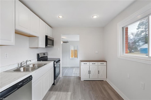 kitchen featuring appliances with stainless steel finishes, a wealth of natural light, sink, and white cabinets