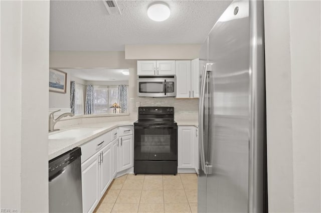 kitchen featuring sink, white cabinetry, light tile patterned floors, appliances with stainless steel finishes, and backsplash