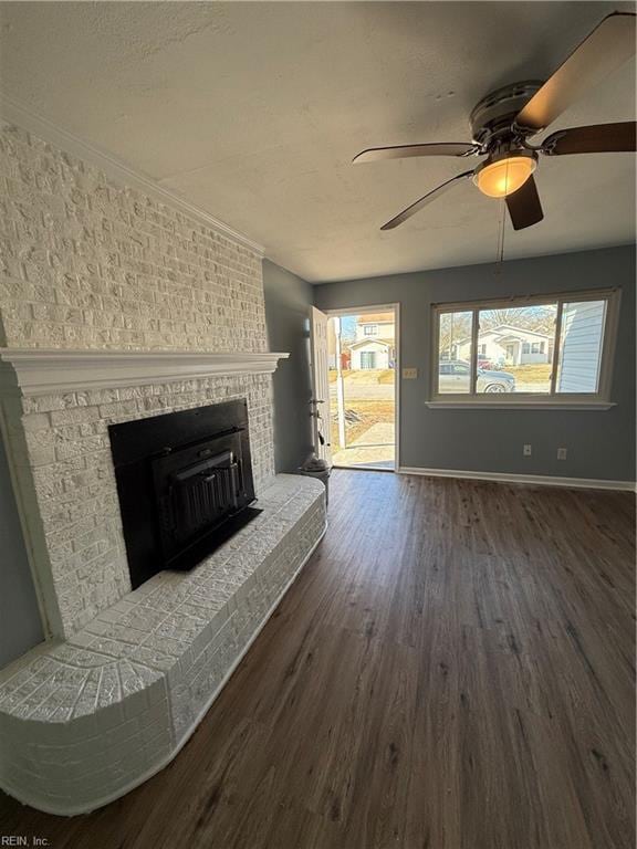 unfurnished living room featuring dark wood-type flooring, ceiling fan, and a brick fireplace