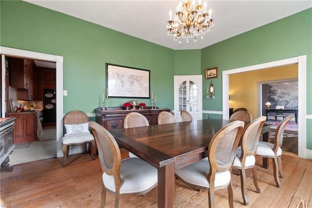 dining area with light hardwood / wood-style floors, french doors, and a chandelier