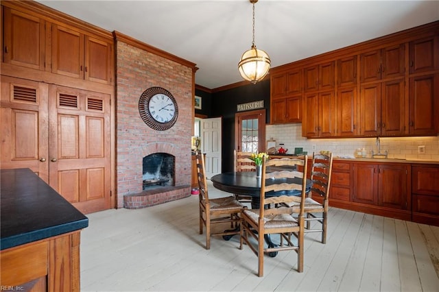 dining area featuring crown molding, sink, a fireplace, and light wood-type flooring