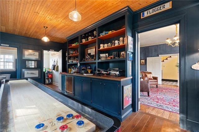 bar featuring dark hardwood / wood-style floors, blue cabinets, wooden counters, hanging light fixtures, and wood ceiling