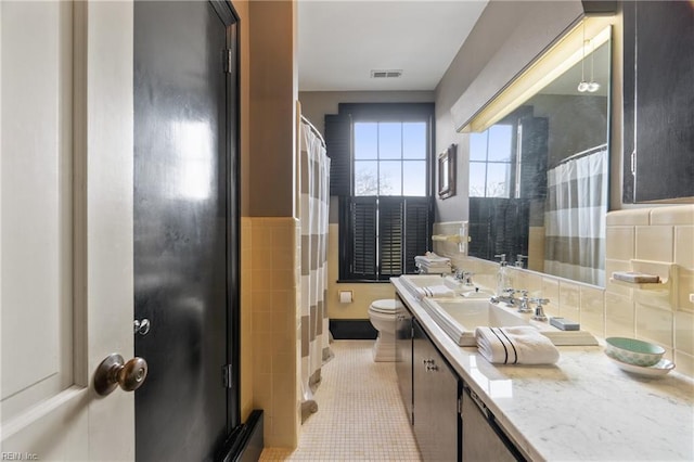 bathroom with vanity, tile patterned flooring, tile walls, and toilet