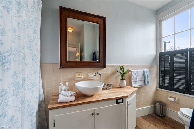 bathroom with tile walls, vanity, and toilet