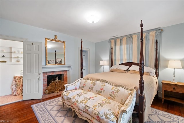 bedroom featuring a brick fireplace and hardwood / wood-style floors